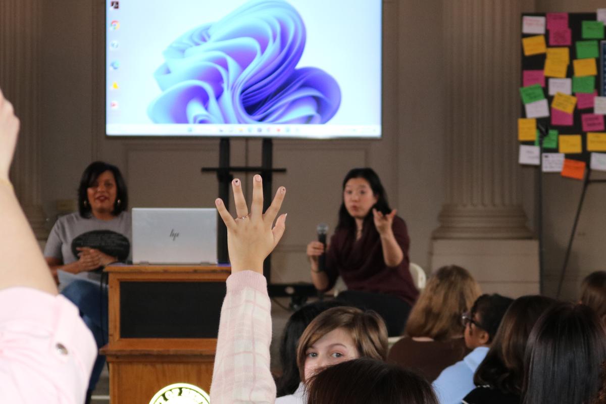 Student raises hand to ask a question to speakers Lisa Fortenberry and Diana Hwang